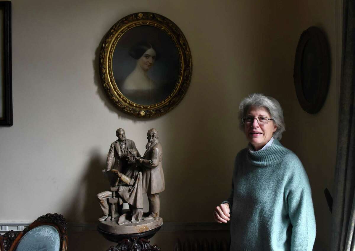 Hart Cluett Museum curator Stacy Draper Pomeroy is pictured with one of her favorite paintings at the Hart-Cluett Mansion on Monday, Dec. 13, 2021, at the Hart Cluett Museum on Second St. in Troy, N.Y. Stacy has been the Hart Cluett Museum curator for 43 years determining how Rensselaer County residents see their local history through the historic rooms she's preserved and exhibits she's curated.