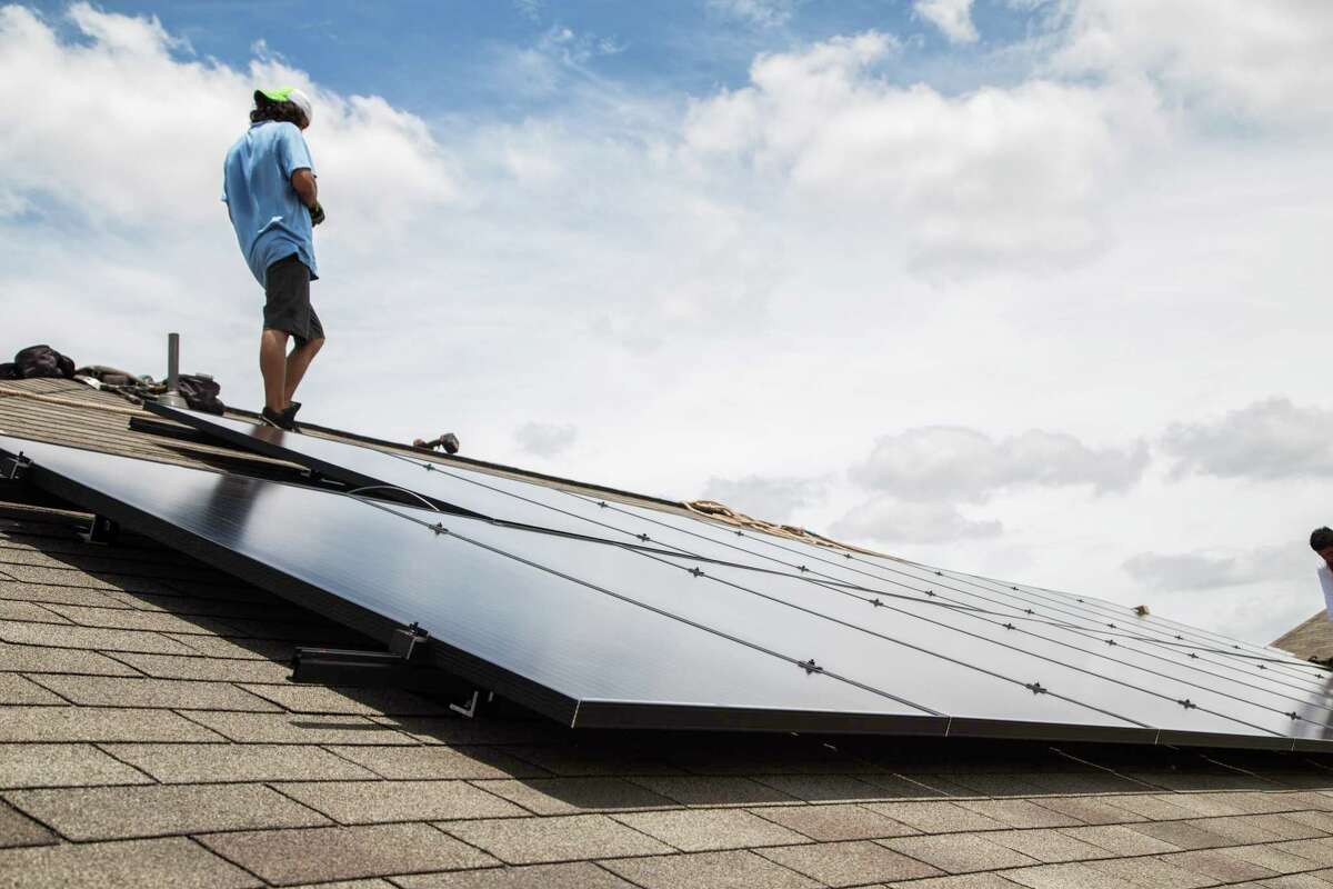 A worker installs solar panels on a home in 2017. Solar is part of Texas’ energy present and future, but a proposal from the Pedernales Electric Cooperative would make solar power more expensive.