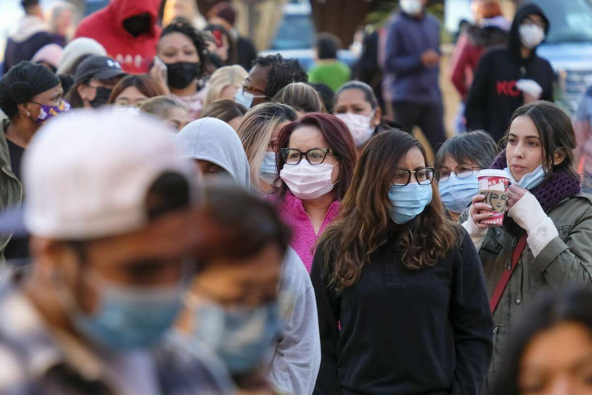 Shoppers wear face masks while waiting to enter a store.