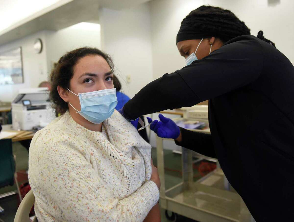 Greenwich's Jazmin Benitez gets her COVID booster from Lakenya McClain on Tuesday in a clinic at the Government Center in Stamford. As infections have risen, the question of whether to keep kids in school or go to remote learning has resurfaced.