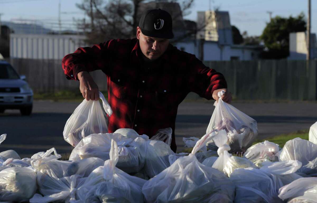 Volunteer John Skoda rearranges bags of food at the S.F. Marin Food Bank pop-up pantry on Treasure Island.
