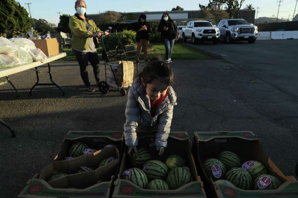 Russell Rodriguez, 4, reaches for a watermelon at the San Francisco Marin Food Bank pop up pantry on Treasure Island in San Francisco, Calif., on Tuesday, December 7, 2021. SF Marin food bank pop-up pantry is held here every Tuesday from 3-5pm, and were a new addition during COVID, where they hand out bags of groceries.