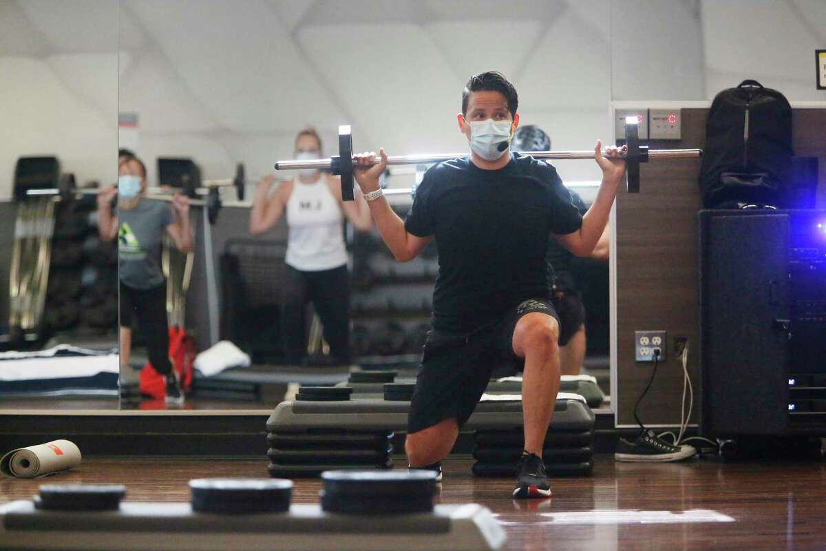 Joe Solis (right), group fitness instructor, wears a mask last July as he teaches a Body Pump class at the 24 Hour Fitness/Redwood City Super Sport. California is imposing a new indoor mask mandate, including for offices and gyms, but allows some counties, like San Francisco, to keep their own less-restrictive rules.
