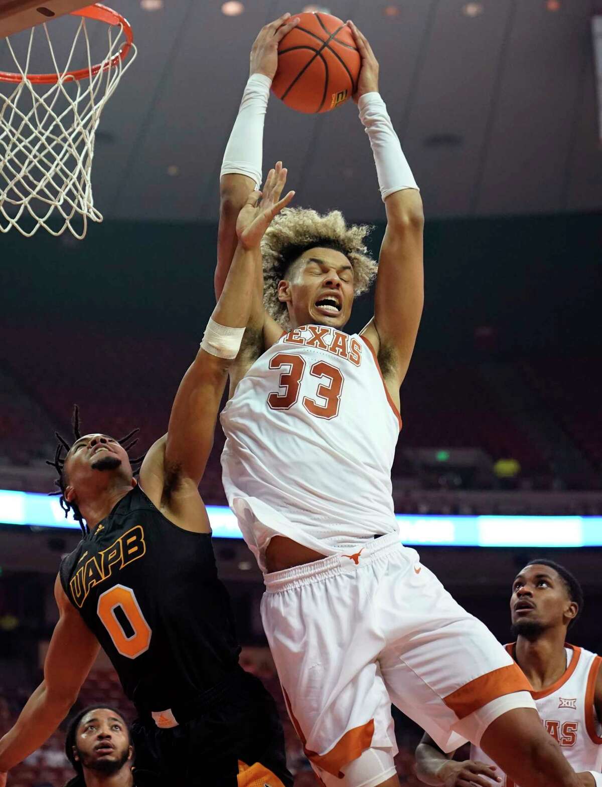 Texas forward Tre Mitchell (33) grabs a rebound over Arkansas-Pine Bluff guard Kshun Stokes (0) during the second half of an NCAA college basketball game, Tuesday, Dec. 14, 2021, in Austin, Texas. (AP Photo/Eric Gay)