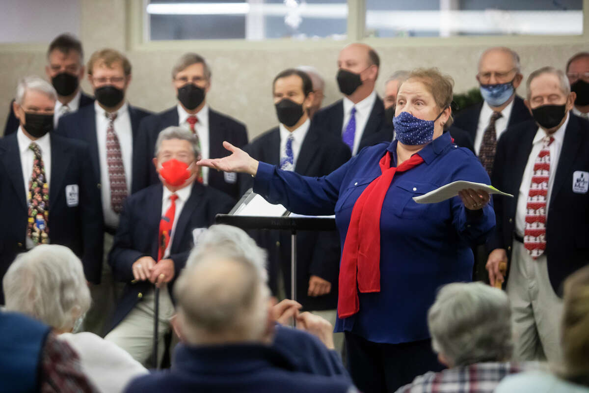 Grace Marra introduces the next song while directing the Men of Music in a concert for residents of Washington Woods senior living community Tuesday, Dec. 14, 2021 in Midland.