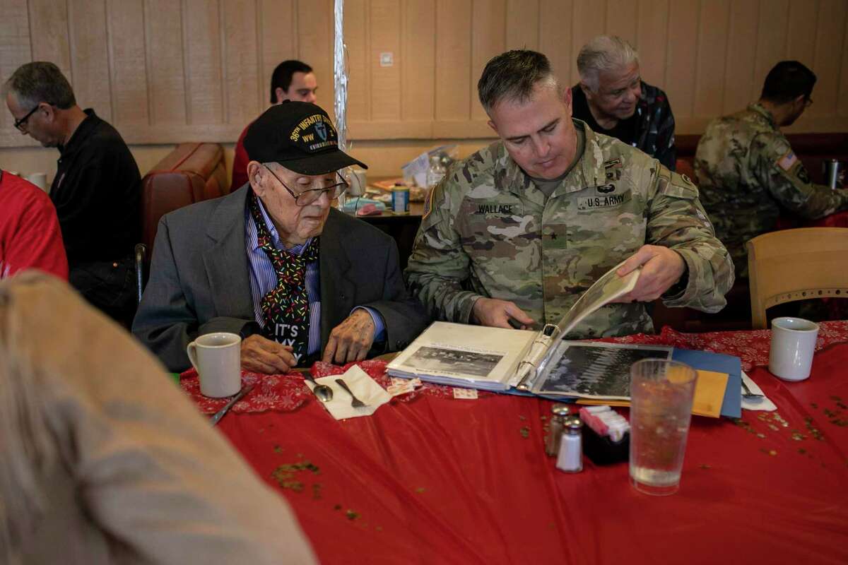 Retired 1st Sgt. Alfred Dietrick looks through a memory book with Brig. Gen. Mike Wallace during Dietrick’s 100th birthday celebration at Jim's restaurant Wednesday. Dietrick was a 36th Infantry Division bazookaman who landed at Salerno in 1943 and is now the oldest living veteran of the Texas Army National Guard’s 36th Infantry Division.