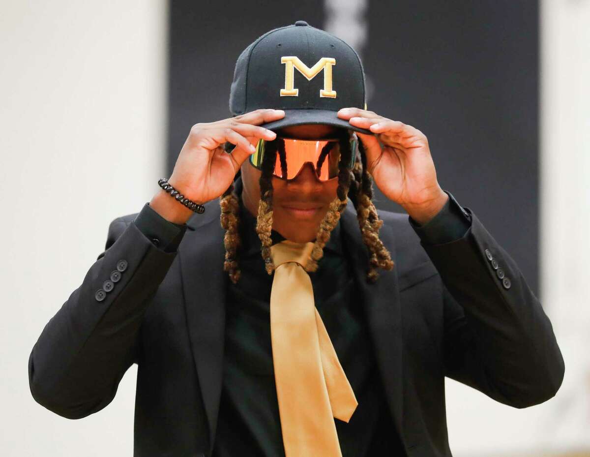 Marcus Scott II adjusts a Missouri hat before signing to play football for the program at Conroe High School, Tuesday, Dec. 15, 2021, in Conroe.