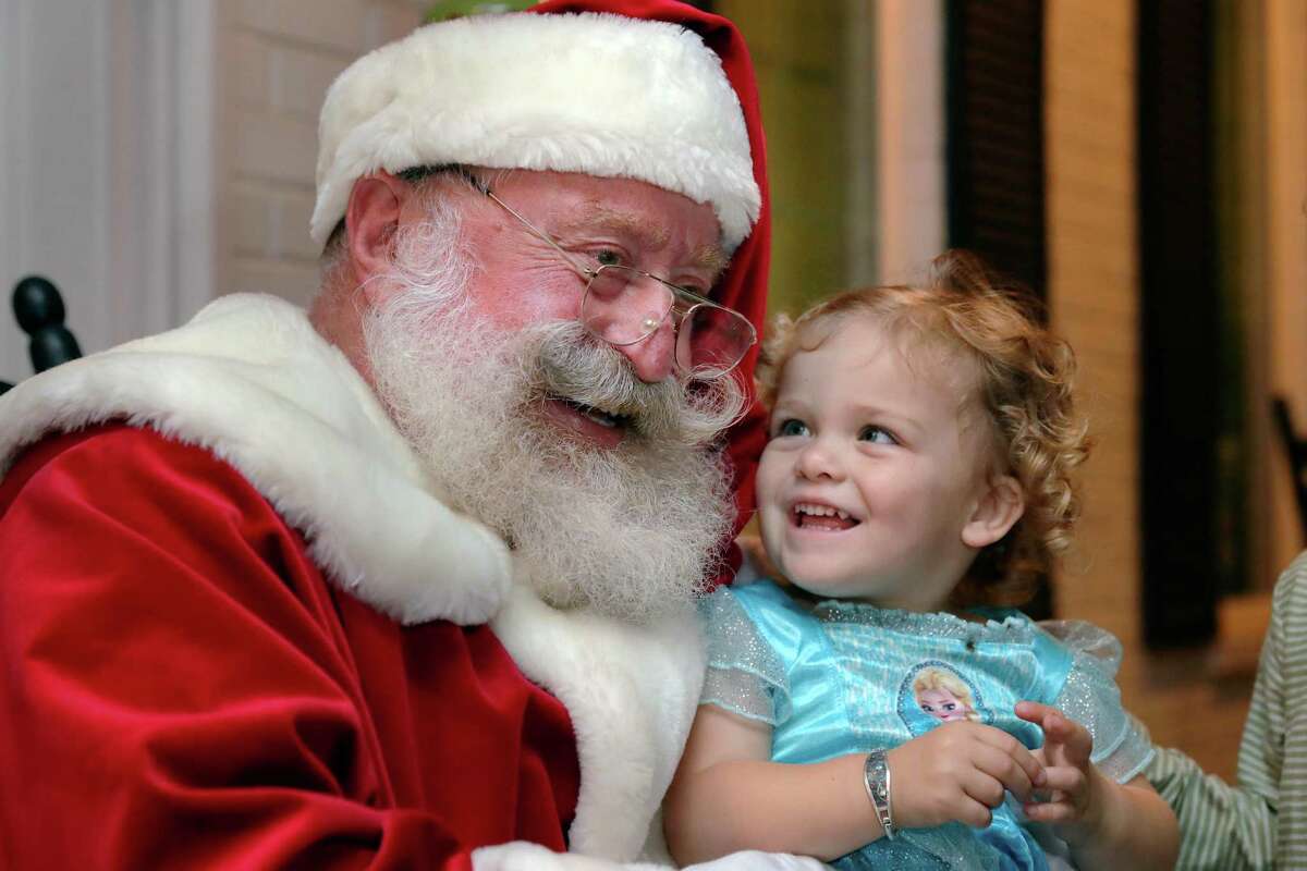 Gordon Taylor, left, as Santa, sits with Etta Ferrell, age two, as he greets neighborhood kids and parents during a block party on Latexo Dr. Friday, Dec. 10, 2021 in Houston, TX.