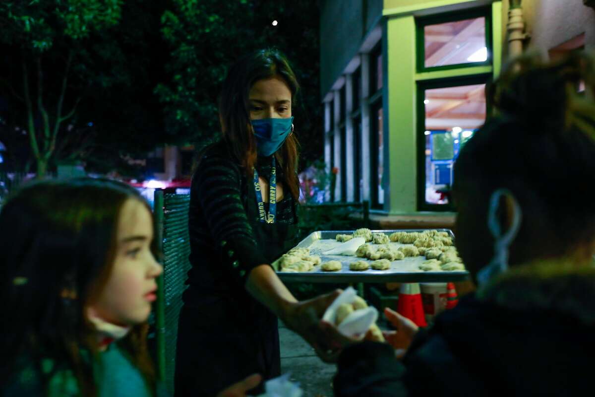 Mary Jane De Castro hands out treats to schoolchildren at the Tenderloin Recreation Center on Tuesday, Dec. 14, 2021 in San Francisco.