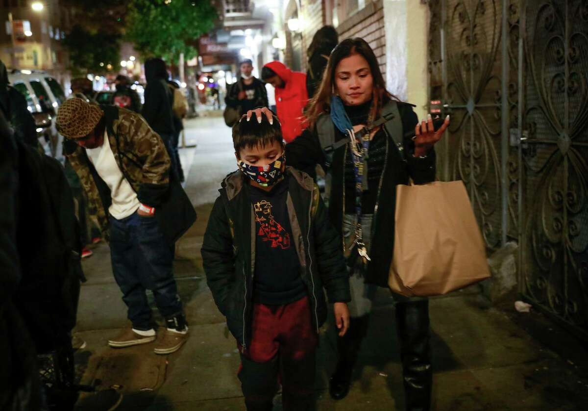 Mary Jane De Castro (right) holds her son Jericho De Castro’s head as she walks home on Tuesday, Dec. 14, 2021 in San Francisco.