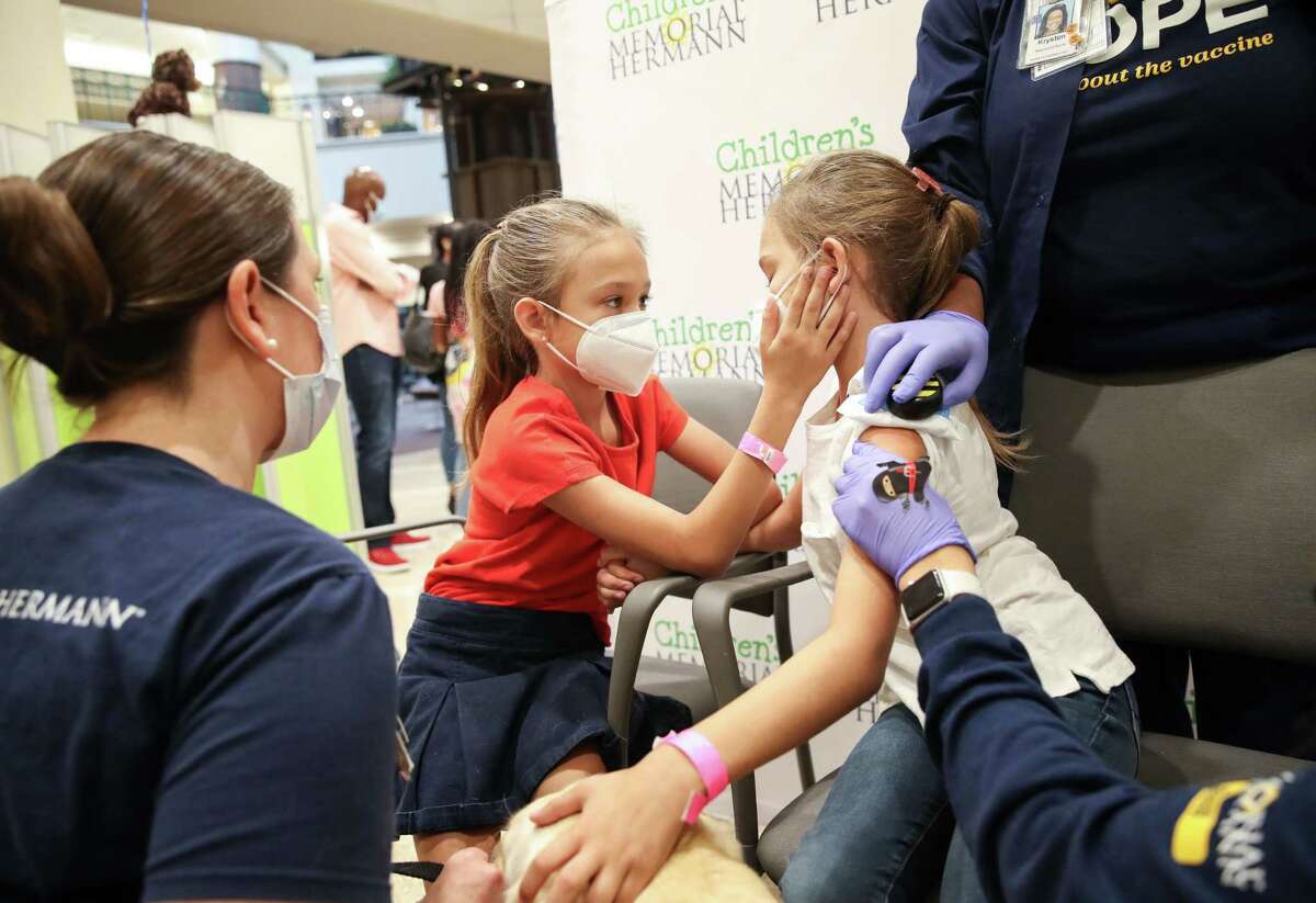 Charlotte Marshall, 9, center-left, comforts her twin sister Claire before she gets her Pfizer pediatric COVID-19 vaccine Wednesday, Nov. 3, 2021, at Children’s Memorial Hermann Hospital in Houston.