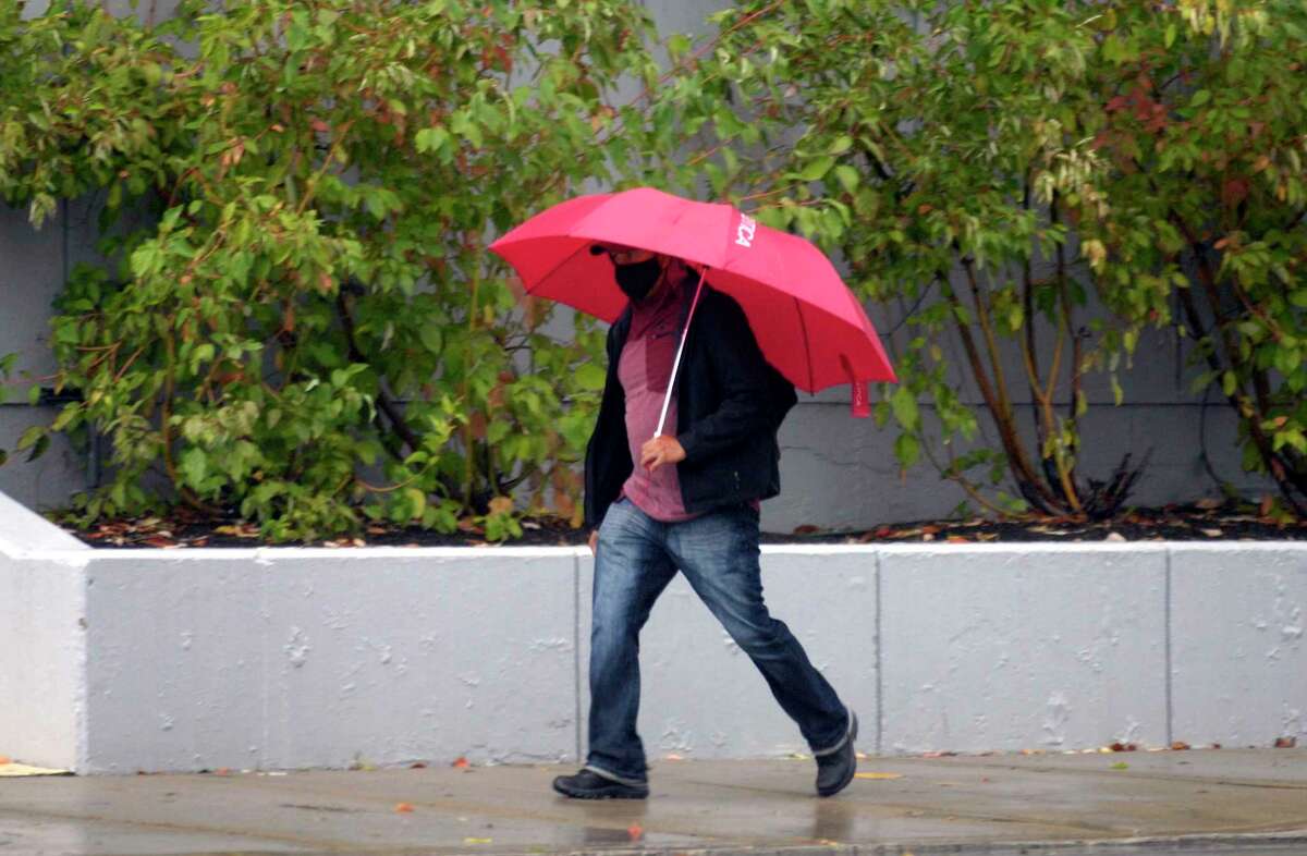 A man walks with his umbrella along Broad Street in Stamford, Conn., on Tuesday October 26, 2021. There will be slight chances for rain Thursday and Friday night this week.