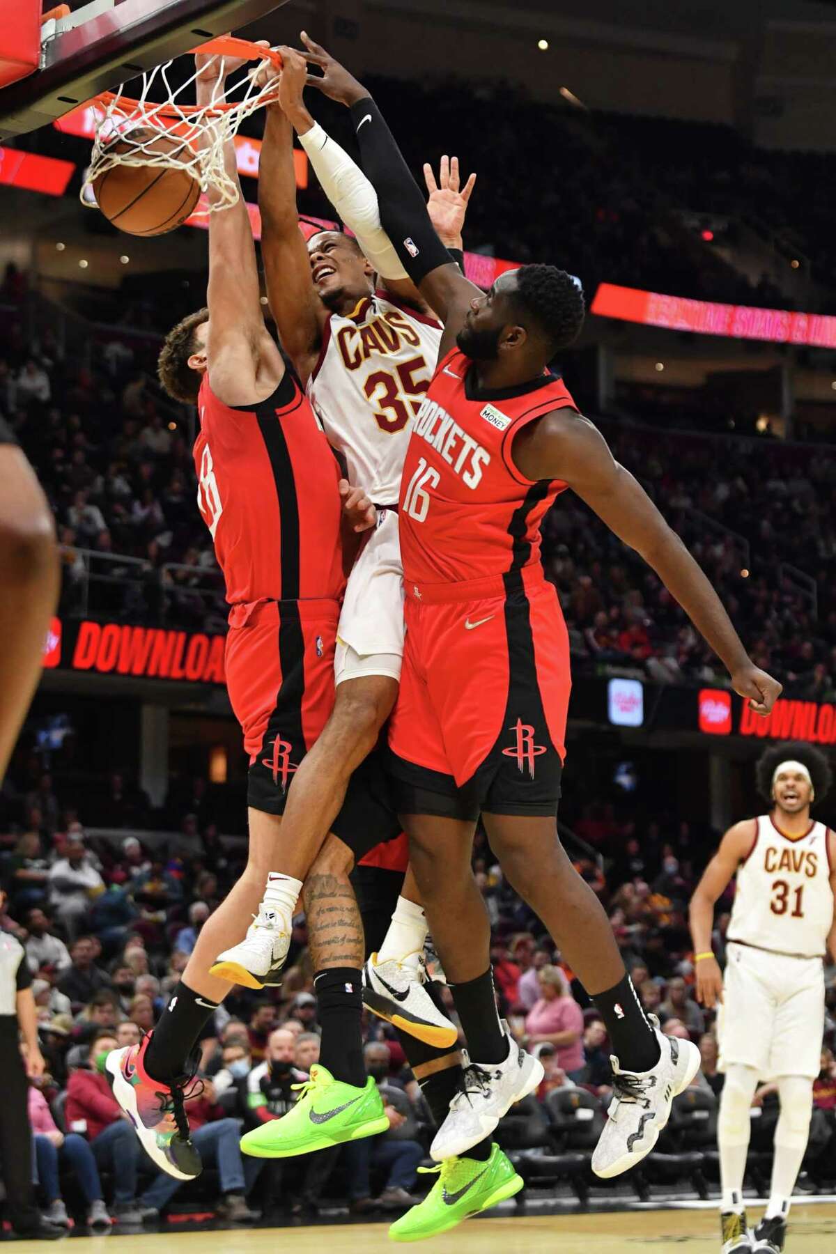 CLEVELAND, OHIO - DECEMBER 15: Isaac Okoro #35 of the Cleveland Cavaliers dunks over Alperen Sengun #28 and Usman Garuba #16 of the Houston Rockets during the third quarter at Rocket Mortgage Fieldhouse on December 15, 2021 in Cleveland, Ohio. The Cavaliers defeated the Rockets 124-89.