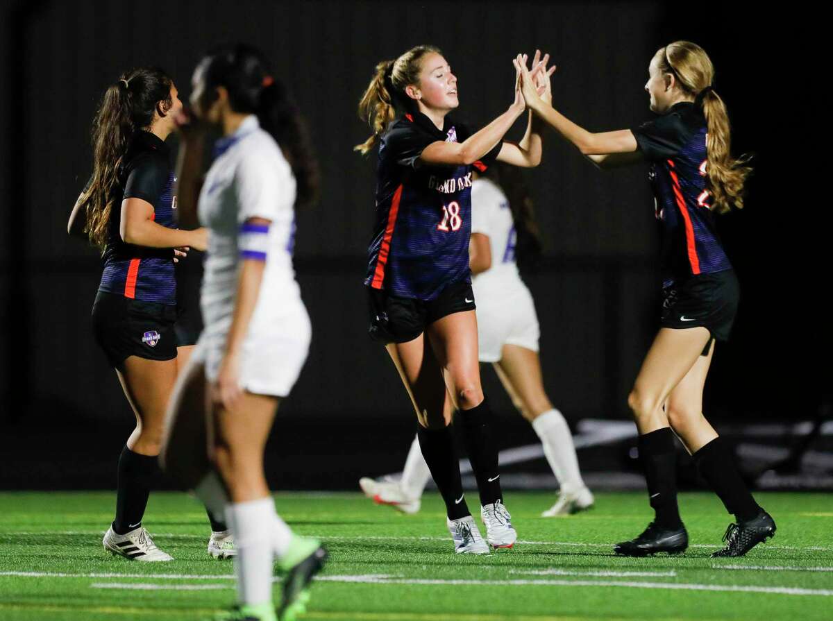 Grand Oaks midfielder Reese Rupe (18) gets a high-five from forward Natalie Buschke (22) after scoring a goal during the first period of a non-district high school soccer match at Grand Oaks High School, Friday, Jan. 22, 2021, in Spring.