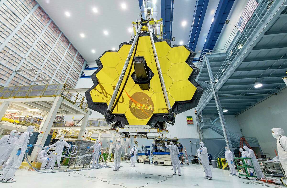 NASA technicians lifted the James Webb Space Telescope using a crane in a clean room at NASA's Goddard Space Flight Center in Greenbelt, Md. The telescope is scheduled to launch Dec. 24. Its gold mirror is designed to capture infrared light from the first galaxies that formed in the early universe.
