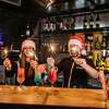 Two bartenders with Santa hats and sparklers making cocktails together on bar counter.