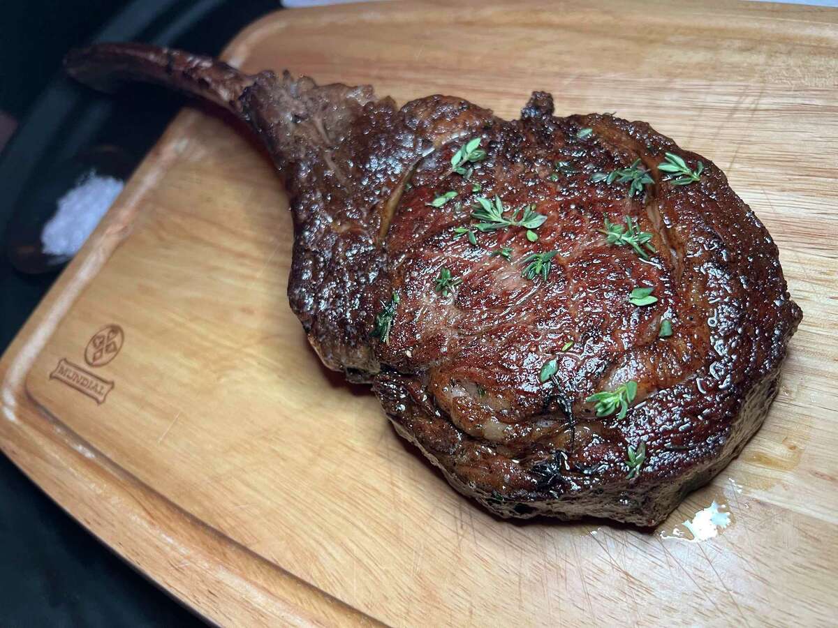 A 32-ounce dry-aged tomahawk steak is served on a cutting board for tableside slicing at Up Scale, a new Southtown restaurant from the owners of Little Em's Oyster Bar.