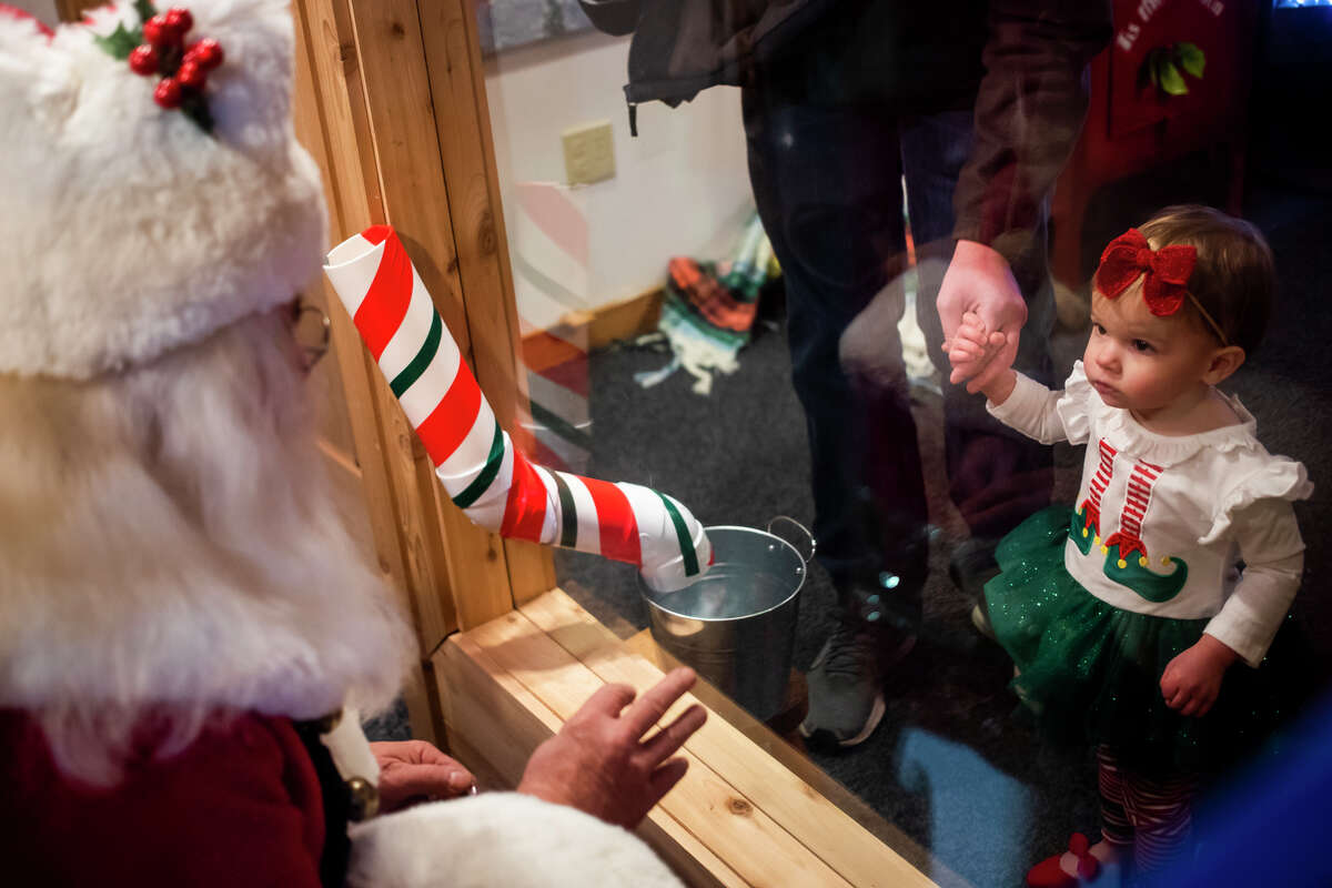 Charlotte Miller, 1, visits with Santa Claus Tuesday, Dec. 7, 2021 at the Santa House in downtown Midland.