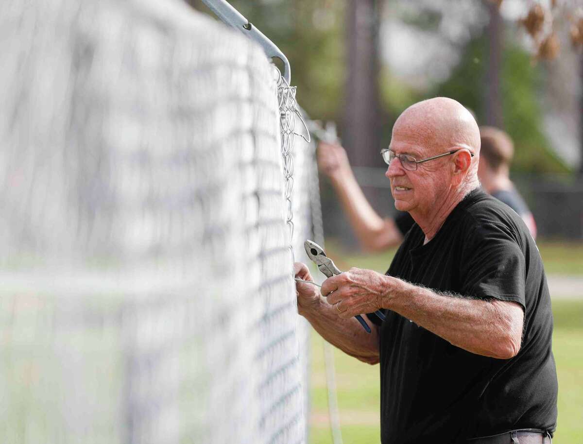 Dick Longer works to install a temporary fence along the back side of the God’s Garage property as the organization prepares to build a new operation facility that will expand their capacity, Thursday, Dec. 16, 2021, in Conroe. The non-profit ministry organization provides vehicles to signal mothers, widows and wives of deployed military members.