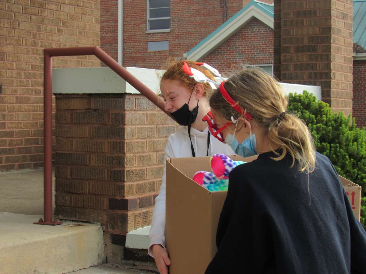 Edie Vetter and Reagan Eldridge work together to carry a box of toys into the house on Main Street.