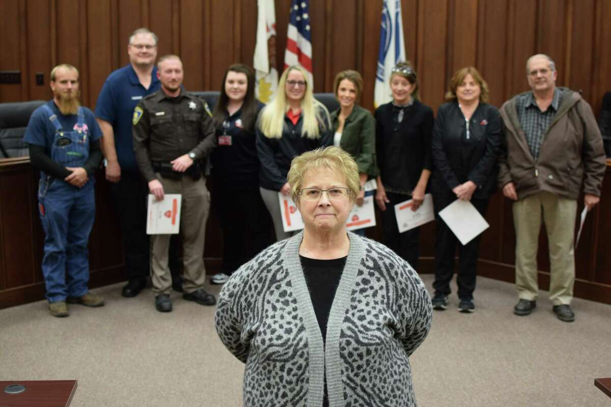 Holly Shanks stands in front of the first responders who saved her life on July 3. From the left, Sam Carpenter, Jason Shumaker, Jamie Bettis, Lynne Bell, JaNece Sweeten, Aleece Ford, Gina Hamilton, Betty Stewart, and Ron Lyons.