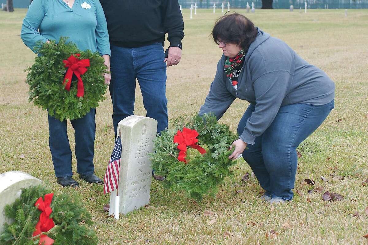 Rachel Rodriguez and Crown Hill Cemetery Association President Mike Murphey watch Sarah White place a wreath on the headstone at the burial site of World War II veteran Miller Leroy Collins at Crown Hill Cemetery in a previous Wreaths Across America event. Veterans buried in that cemetery and at Grand View Funeral Home and Memorial Park/Bethany Cemetery will be honored in observances on Dec. 18.