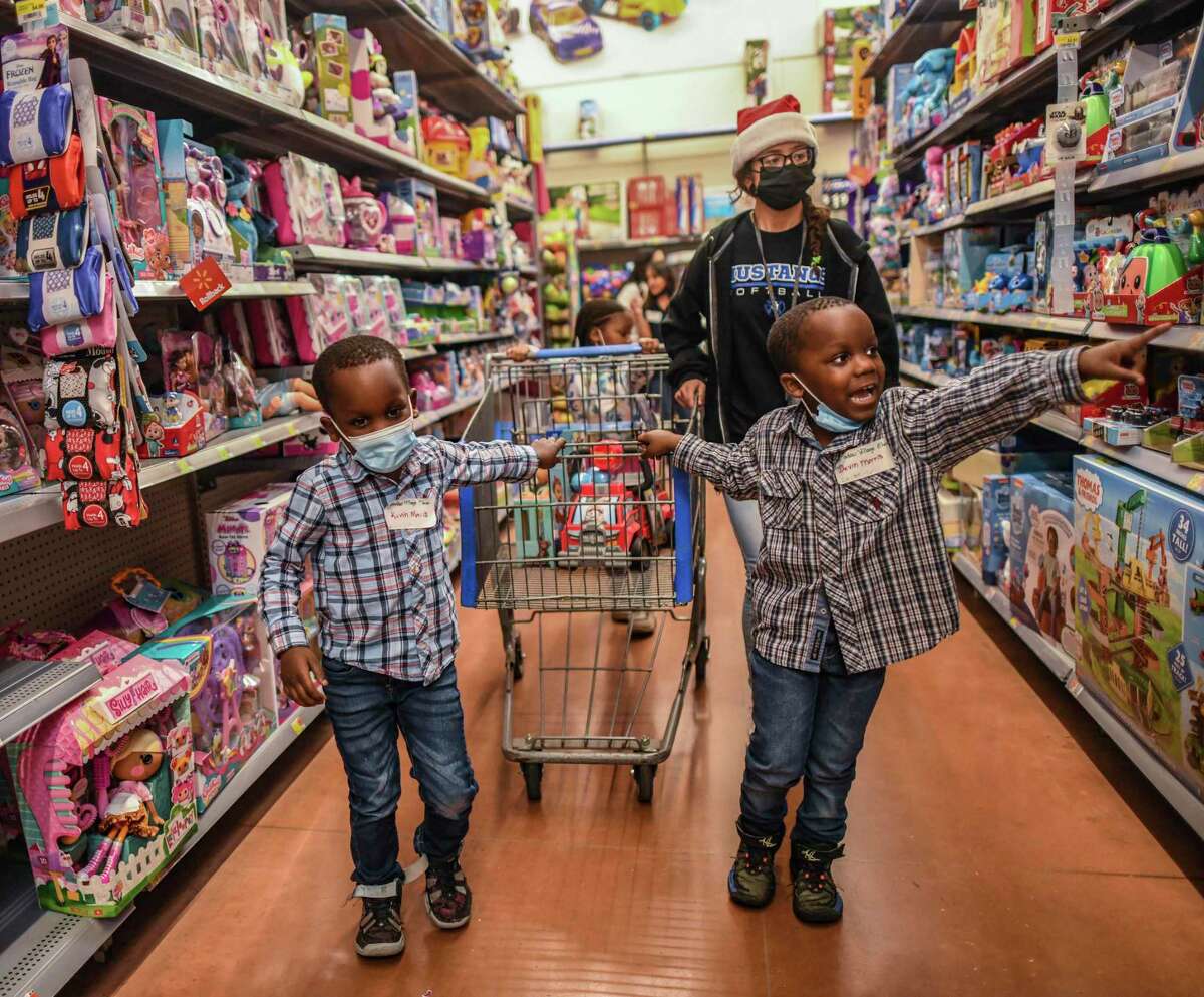 Brothers Kevin, left, and Devin Morris, escorted by Jasmine Rojas, choose toys at the Walmart at 8923 W. Military Drive on Thursday. John Jay High School students raise money every year to let kids get $50 worth of shoes and toys.