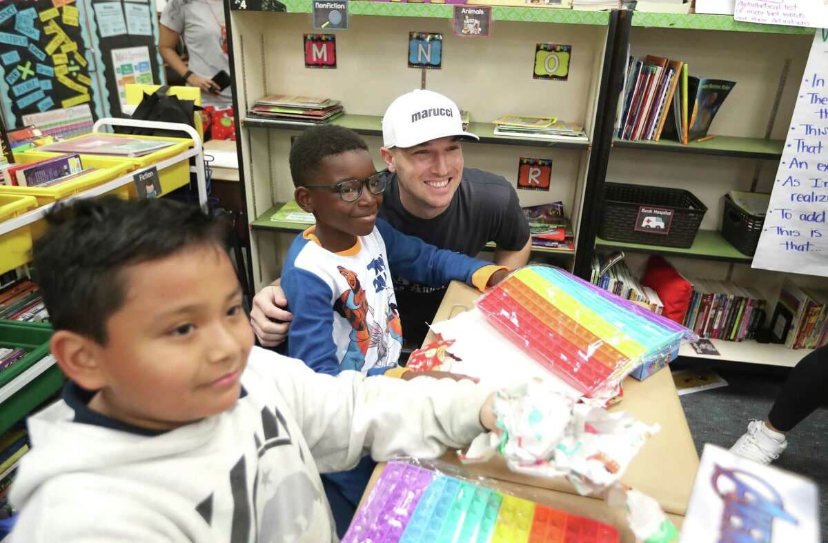 Houston Astros third baseman Alex Bregman takes a photo with Aiden Lavailas, 9, after giving him a wrapped present, as he and his wife, Regan Bregman helped to distribute toys to each student at Thornwood Elementary, Thursday, Dec. 16, 2021 in Houston . This is being done in partnership with Lily’s Toy Box, a nonprofit organization that is a Spring Branch ISD Good Neighbor. Lily’s Toy Box has adopted Thornwood Elementary.