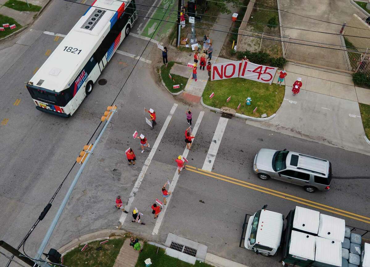 Volunteers with the organization Stop TxDOT I-45 walk with signs across the crosswalk during a demonstration at the intersection of Polk Street and St. Emmanuel Street just east of downtown Houston on Sept. 3, 2020.