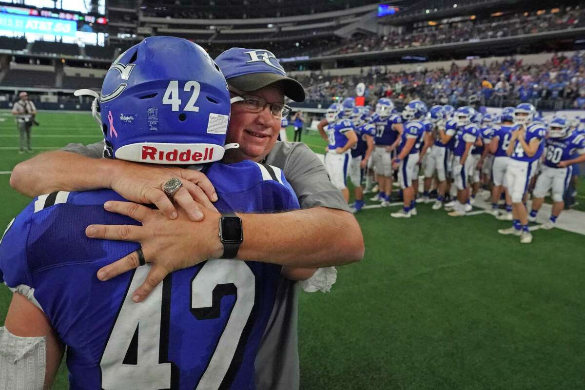 Falls City head coach Mark Kirchhoff hugs senior Grant Jendrusch (42) after the Falls City High School Beavers lose to the Stratford High School Elks in the Class 2A Division II state championship football game on Thursday, December 16, 2021 at AT&T Stadium in Arlington, Texas. Stratford won 39-27. CREDIT: Louis DeLuca for the San Antonio Express News