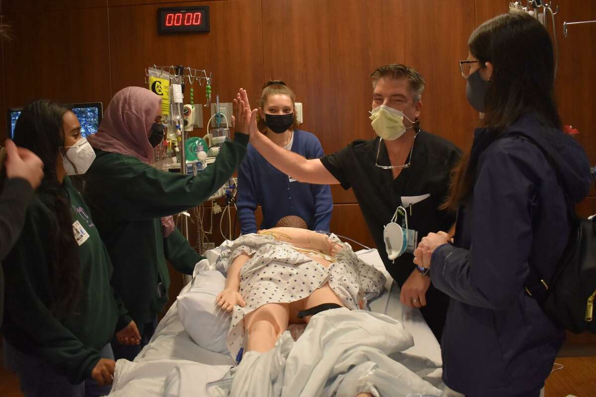 From left to right, Stamford high school students Tasneem Tayab, Maisha Mumtahin, Victoria Gibek, Dr. Frantz Hastrup, director of critical care at Stamford Hospital, and student Nina Lopes, participate in an exercise with a mannequin meant to simulate the experience of turning over a patient with COVID-19 to allow for better air flow to their lungs.
