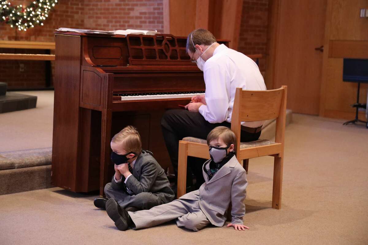 Music director Zach Stegman finalizes his notes for the four concerts on Sunday evening as his two sons, in 1st grade and kindergarten, patiently wait for the concert to start and their turn to sing.