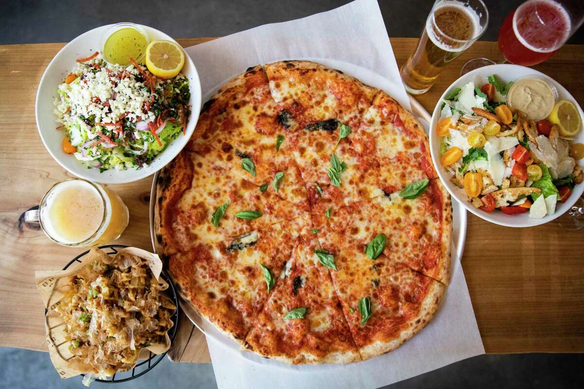 Clockwise from top left: Chopped salad, cheese pizza, Caesar salad and Bulldog fries with a selection of local beers at SSP Beer Hall in SoMa, chef Dennis Lee’s new beer hall.