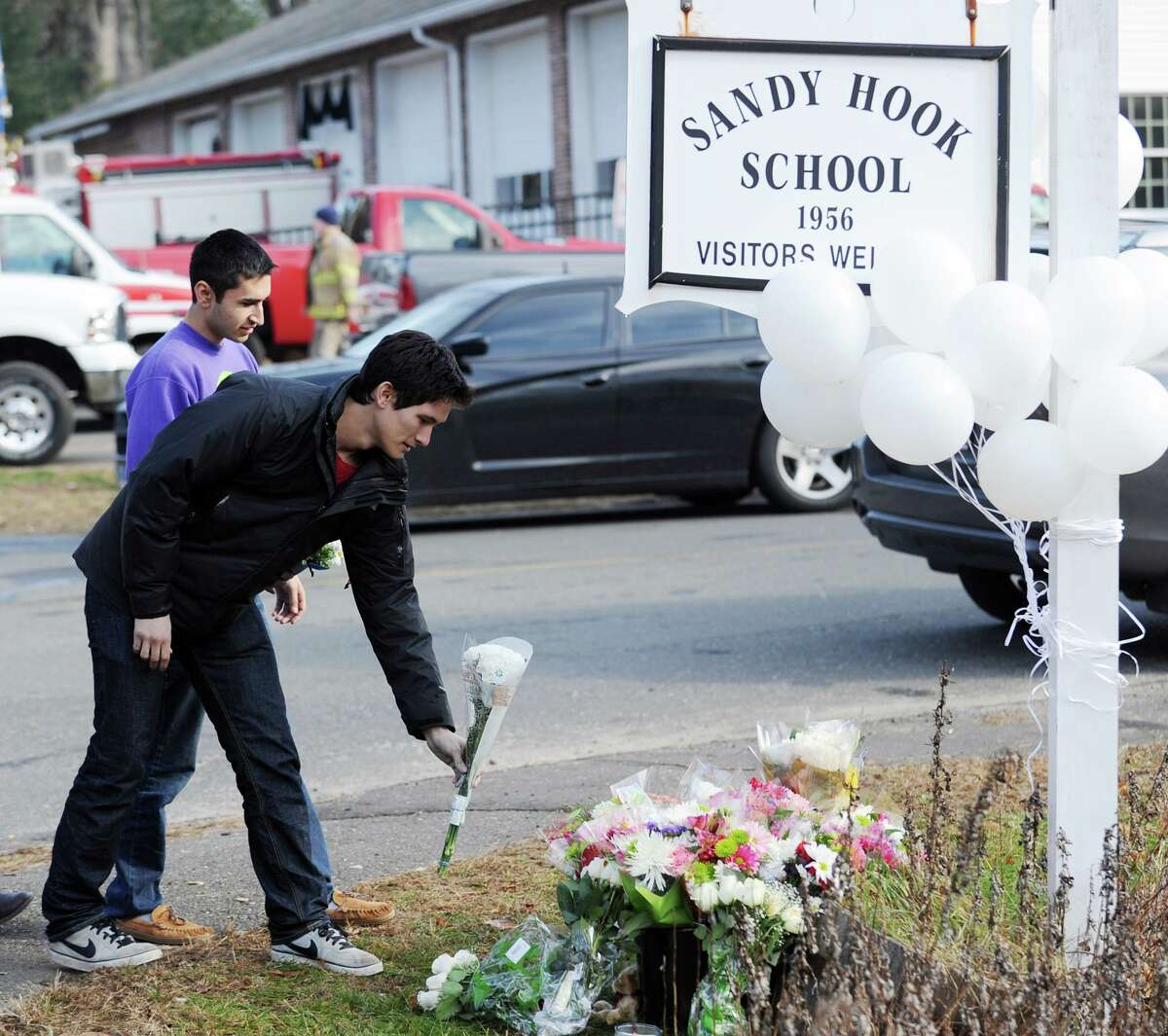 Mourners place flowers near the Sandy Hook Elementary School sign in Sandy Hook, Conn., Saturday, Dec. 15, 2012.