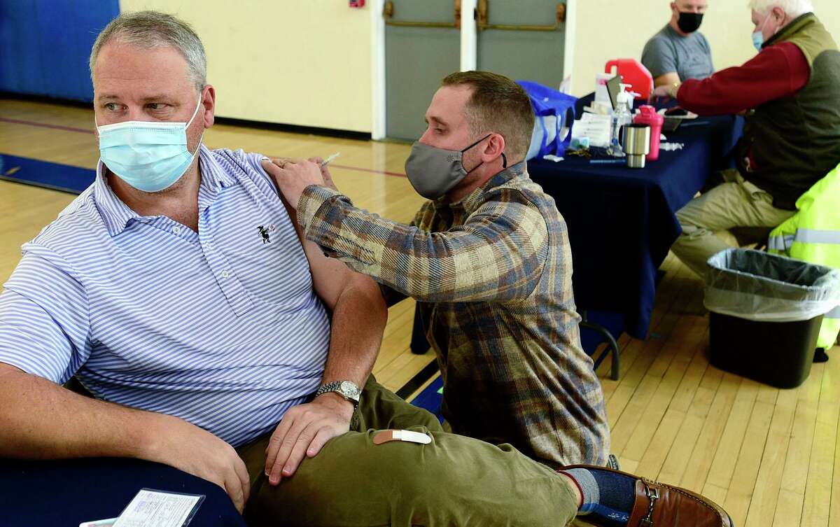 Greenwich residentt Doug Conrod receives his vaccination dose from EMT Kyle Rothschild during the Darien booster clinic Tuesday, December 7, 2021 at Town Hall in Darien, Conn.