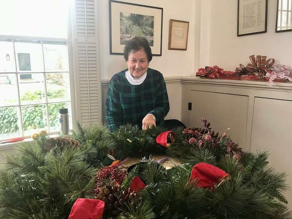 Wilton Garden Club member Sue Wall is recently pictured at work embellishing the wreath, which now graces the Wilton Library. Wilton Garden Club members recently gathered at Old Town Hall, and created 20 arrangements, and the wreath. Wilton Garden Club members work on the project in concert with the Wilton Social Services Department every December.