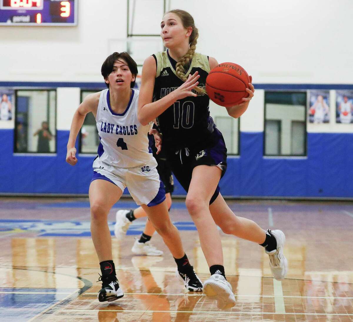 Montgomery point guard Savannah Piro (10) drives past New Caney small forward Tori Perales (4) during the first quarter of a high school basketball game at New Caney High School, Friday, Dec. 17, 2021, in New Caney.