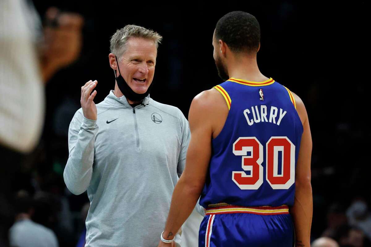 Golden State Warriors head coach Steve Kerr, left, talks with Stephen Curry during a break in action during the first half of an NBA basketball game against the Boston Celtics, Friday, Dec. 17, 2021, in Boston. (AP Photo/Mary Schwalm)