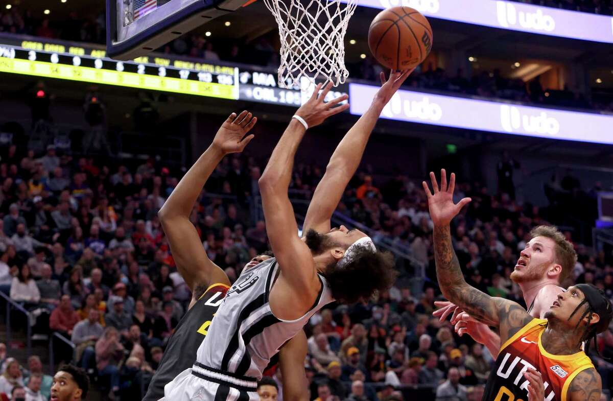 San Antonio Spurs guard Derrick White, left, attempts a layup as San Antonio Spurs center Jakob Poeltl, middle, and Utah Jazz guard Jakob Poeltl, right, look on during the first half of an NBA basketball game on Friday, Dec. 17 2021, in Salt Lake City. (AP Photo/Kim Raff)