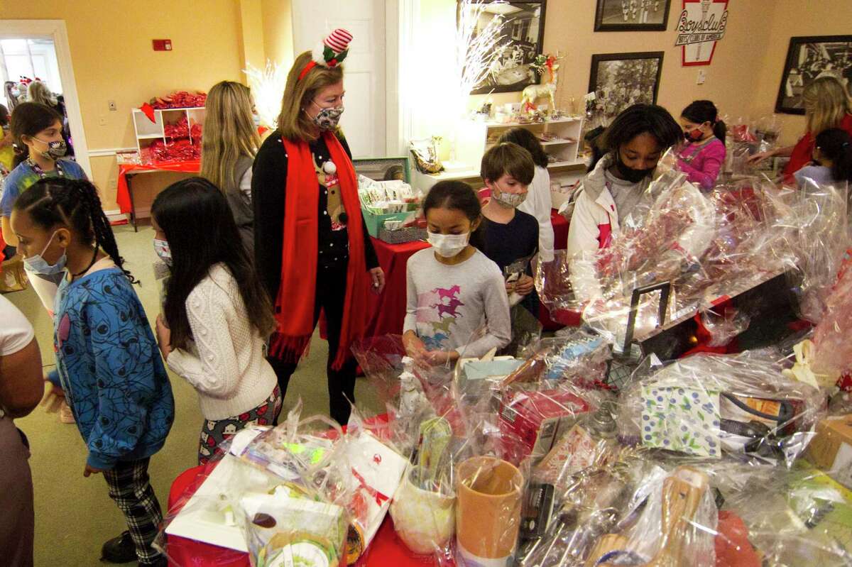 Volunteer Anne DeNaut is on hand to help kids pick out presents during the Boys and Girls Club's Holiday Party in Greenwich, Conn., on Thursday December 16, 2021. Also on hand were members of Greenwich High School's Give Back Club, who handed out snuggle blankets to each child.