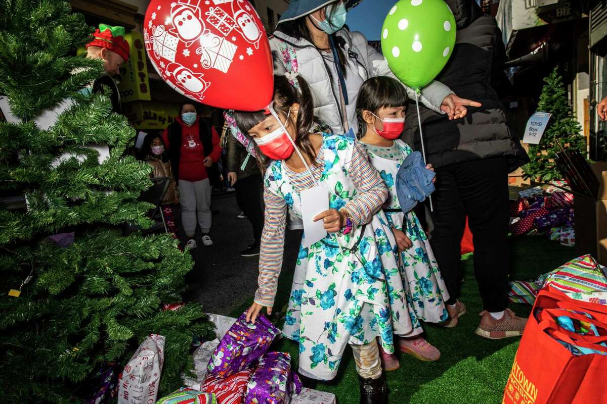 Six-year-old Emily Chan (left) and sister Mei Mei, 5, look for a gift during a toy giveaway.