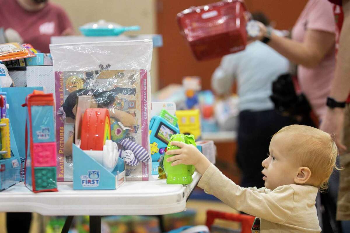 One-year-old Andrew Adam picks out toys for his parents to wrap during Santa’s Firefighter Toy Drive Wrap Party at the Fire Training Academy in San Antonio.