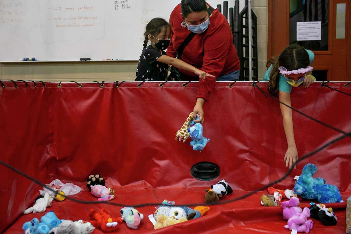 7-year-old Oleisa Aguirre with her mother Julie Aguirre points to a toy he loves. Emberly Buckley, 7, searches for a present for herself. The three were at the Santa Claus Firefighter's Toy Drive Closing Party at Fire Training Academy in San Antonio.