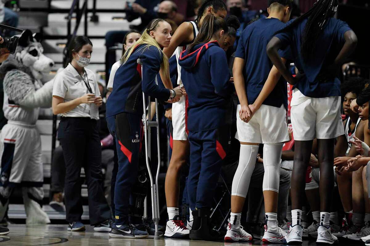 UConn’s Paige Bueckers uses crutches as her team huddles for a timeout in the second half against Louisville on Sunday.