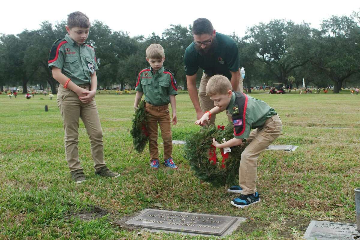 Brandon Crawford and sons Carter and Fletcher watch as son Levi places a wreath near the marker of U.S. Army World War II veteran Dee Rex Brous during a National Wreaths Across America event at Grand View Cemetery in Pasadena.