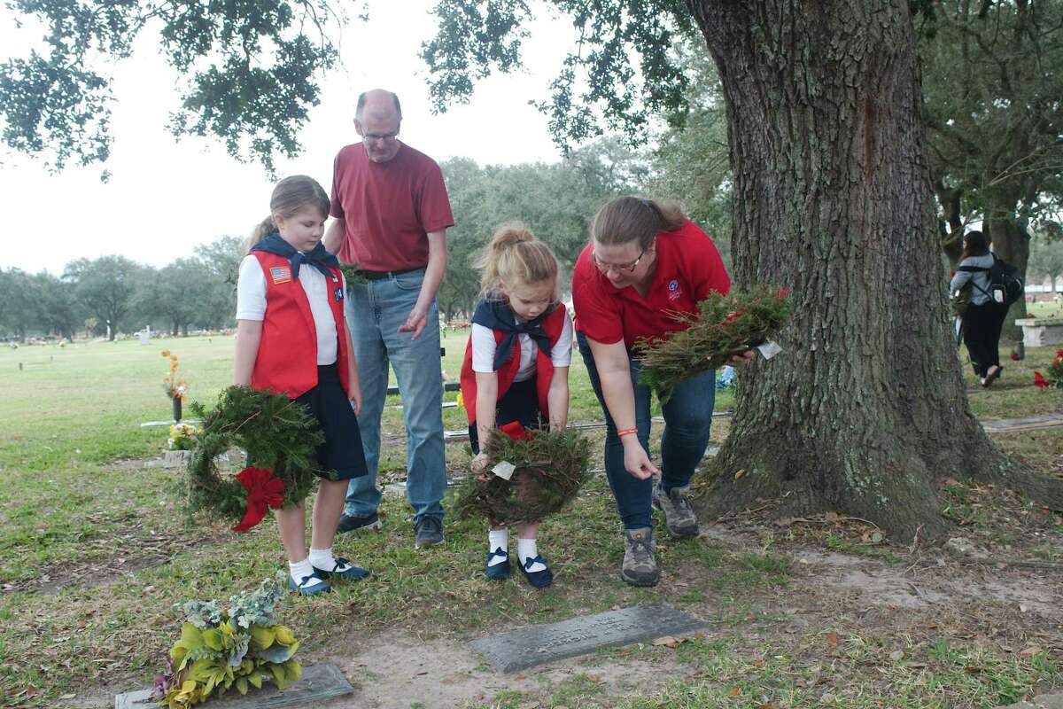 Mark Hall and daughter Margaret watch as his wife Melinda assists daughter Madeline in placing a wreath near the marker of U.S. Army World War II veteran Melton Nickerson at Grand View Cemetery.