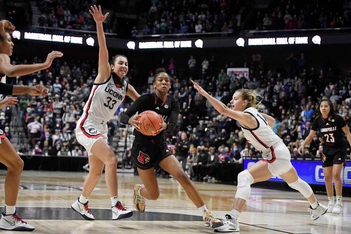 Louisville's Kianna Smith (14) splits the defense of Connecticut's Caroline Ducharme (33) and Dorka Juhasz (14) in the second half of an NCAA college basketball game, Sunday, Dec. 19, 2021, in Uncasville, Conn. (AP Photo/Jessica Hill)
