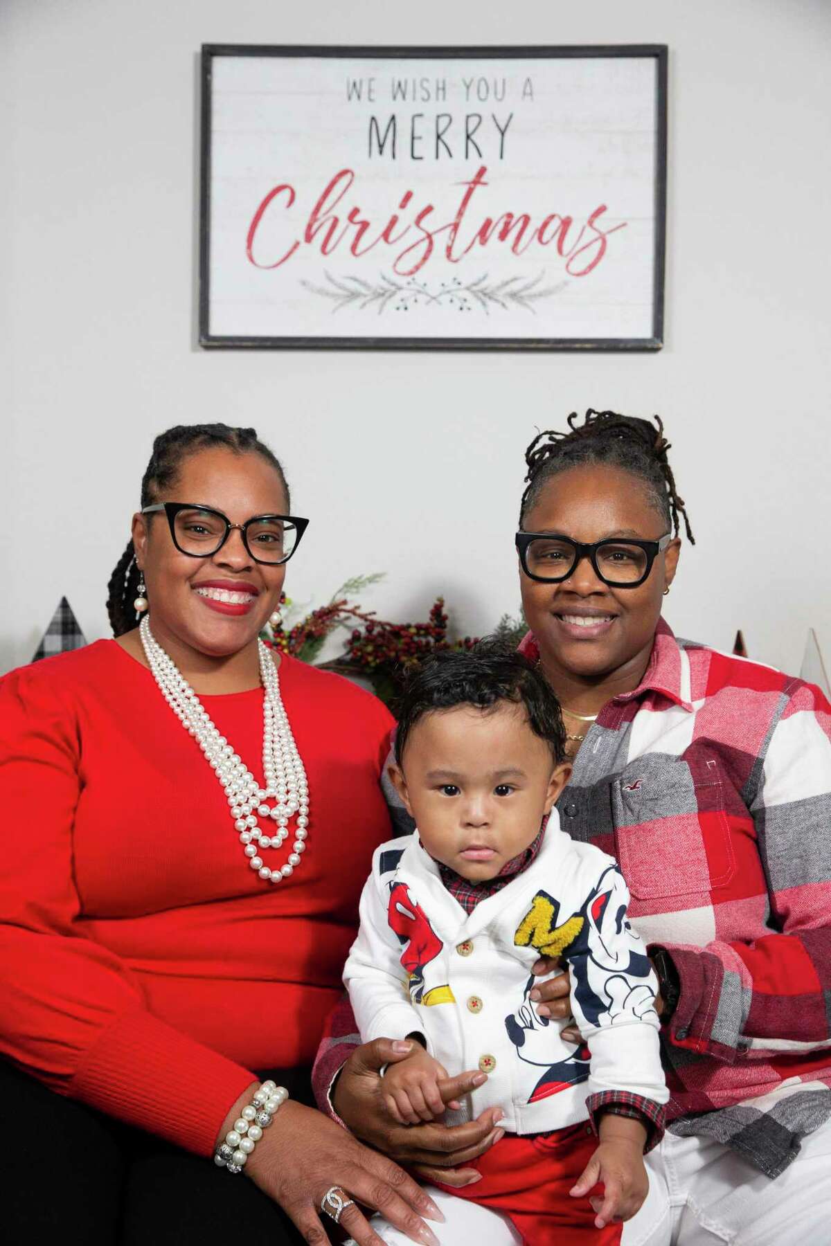 Eighteen-month-old Asher A. Tate takes a photograph with his mothers Tameka Tate, right, and Felecia Garner, both 41, Tuesday, Dec. 7, 2021, in Houston. Asher was born at 23 weeks into the pregnancy and given a 10 percent chance of survival, spent five months in NICU. This year will be Asher’s first Christmas at home.