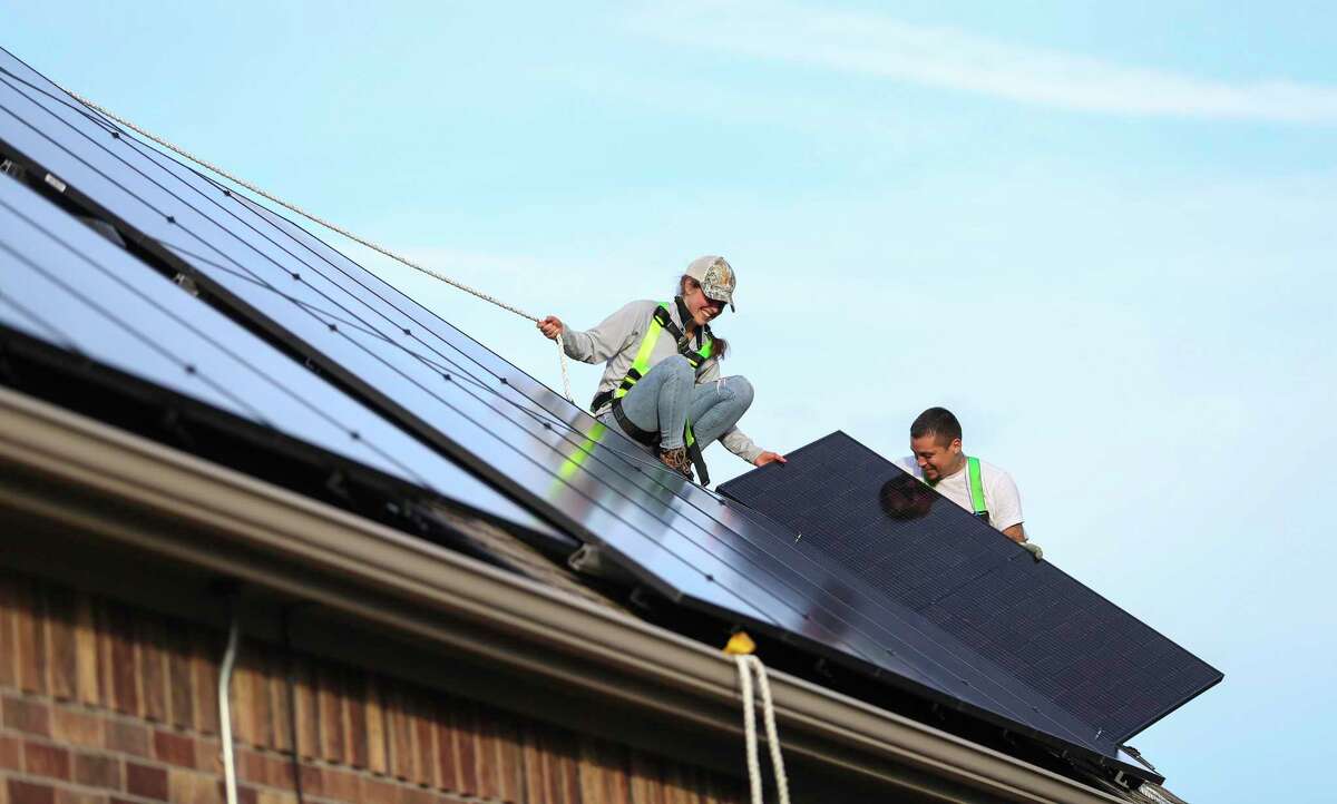 Laura Masterson and Daniel Molina, with Texas Solar Outfitters, install solar panels on a home, Friday, Dec. 17, 2021 in Cypress. Under new building code adopted by the city of Houston, new home developers will have to map out roof space for solar panels and make sure there is room for the wiring.