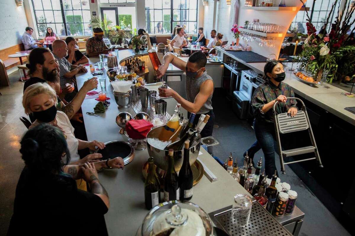 朱利安·阿雷奥拉(中)在奥克兰的“朋友和家人”餐厅为顾客制作饮料。在员工可能接触到冠状病毒后，酒吧暂时关闭。